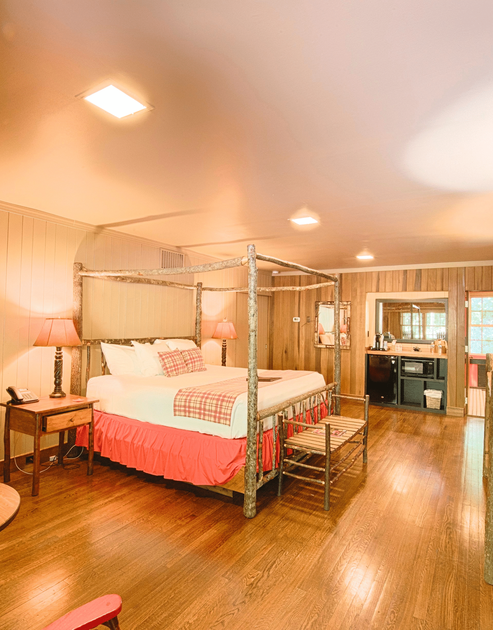 a bedroom with cozy interiors and wooden flooring featuring a double bed along with seating area with a round coffee table - Historic Tapoco Lodge