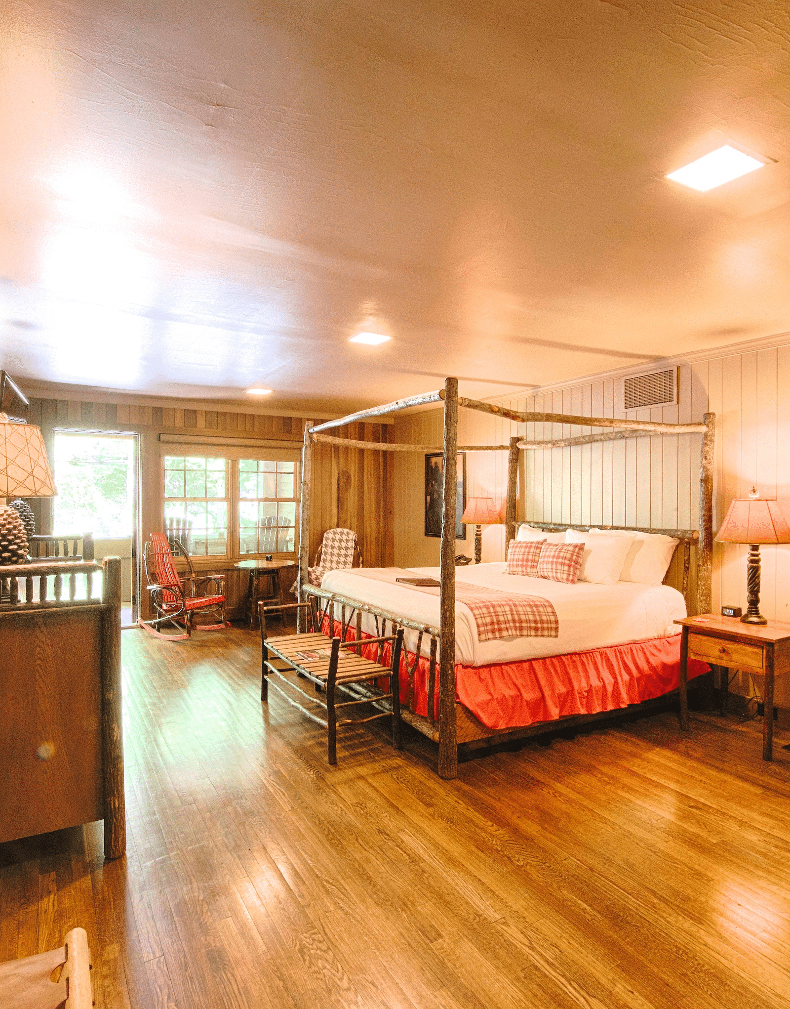 corner view image of a bedroom with a wall mounted picture along with a double bed and a door allowing bright natural light into the room - Historic Tapoco Lodge