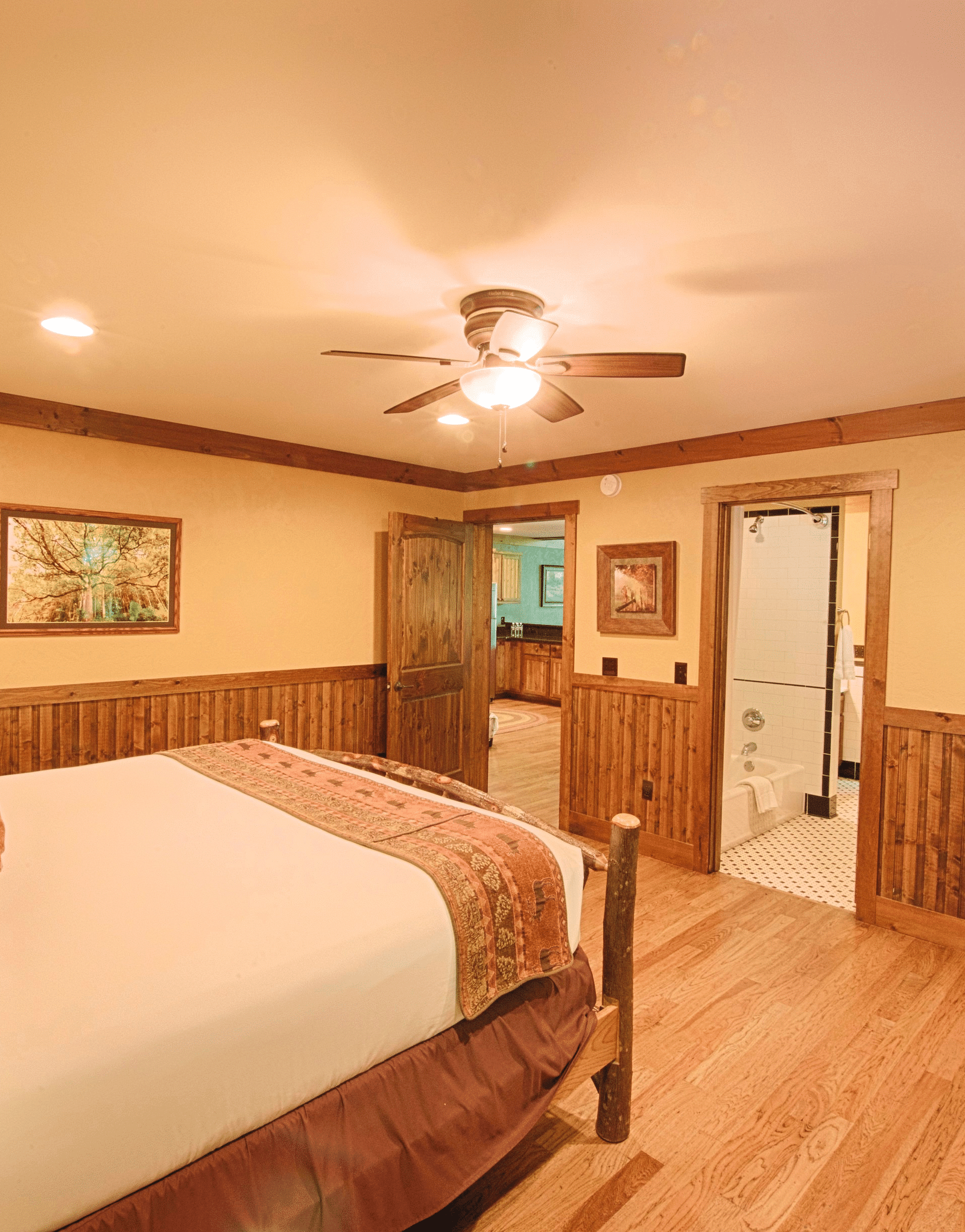 side view image of a bedroom with a double bed along with a wall mounted television in front of it - Historic Tapoco Lodge