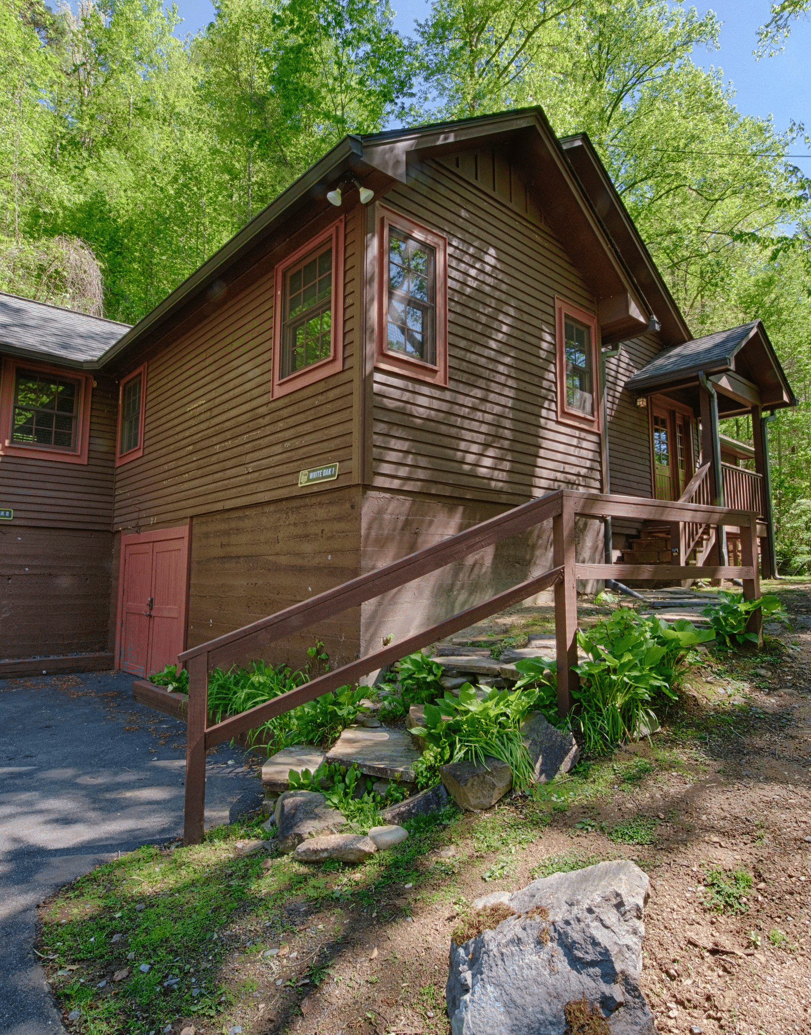 corner view of a cabin with wooden exterior surrounded by lush green trees - Historic Tapoco Lodge
