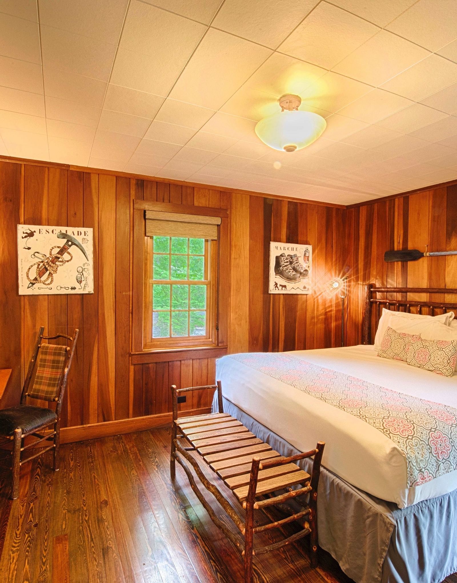 a room with wooden walls featuring a double bed with soft pillows arranged over it along with a wall mounted television right in front of it - Historic Tapoco Lodge