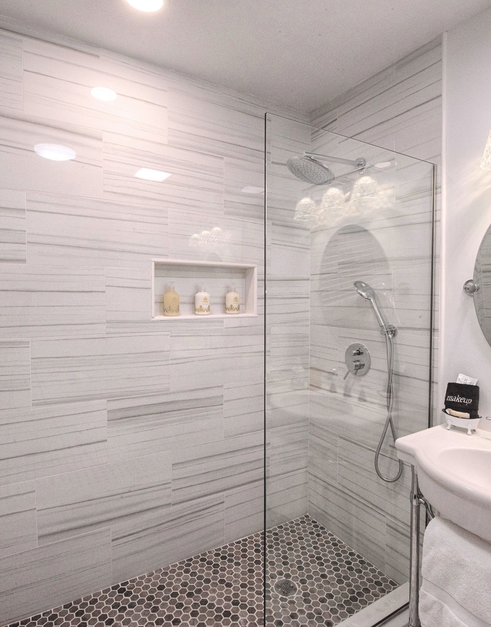 a bathroom with grey gradient tiles with a separate shower area and a circular shaped mirror - Historic Tapoco Lodge