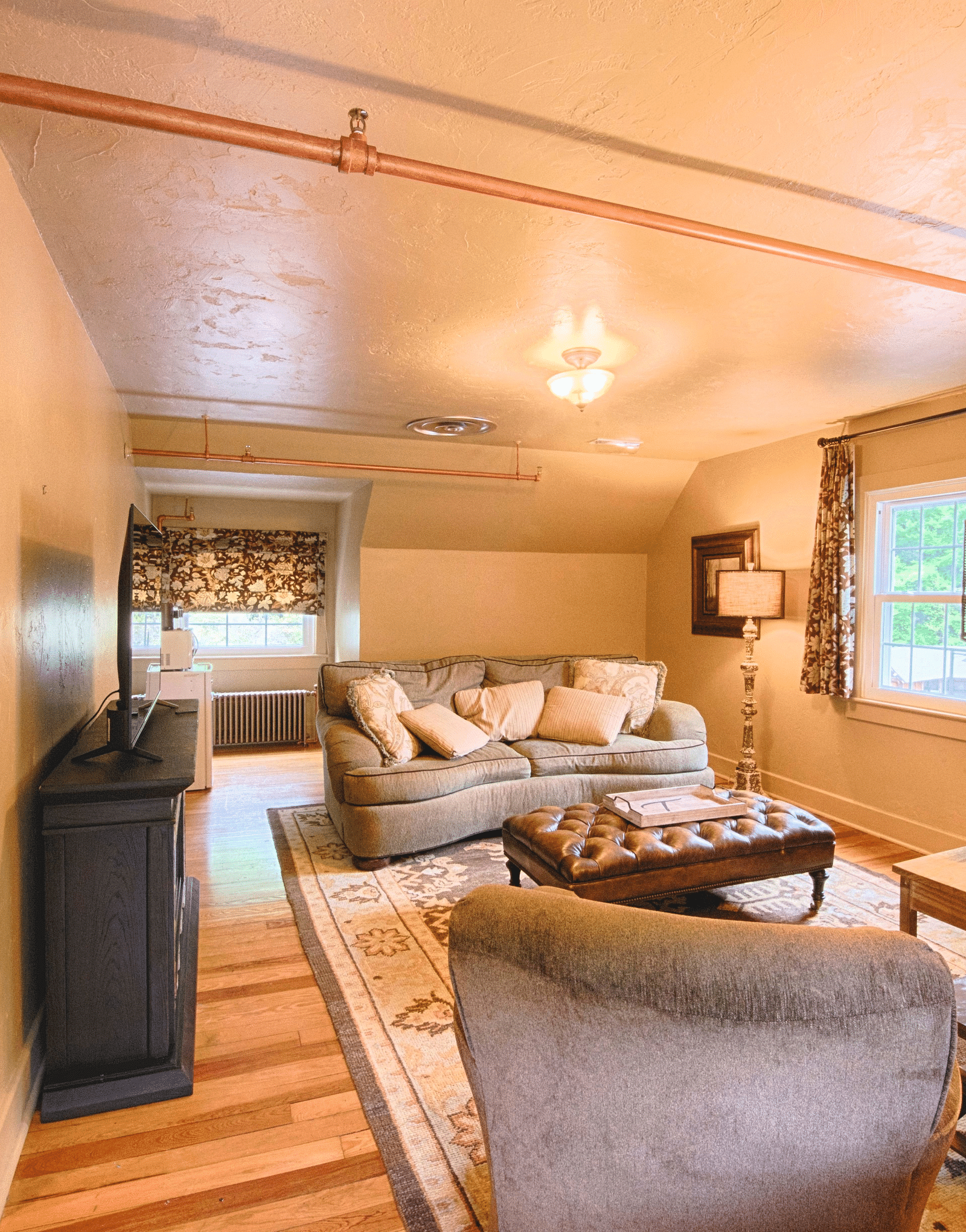 a spacious living room featuring a plush couch and two arm chairs in front of it - Historic Tapoco Lodge