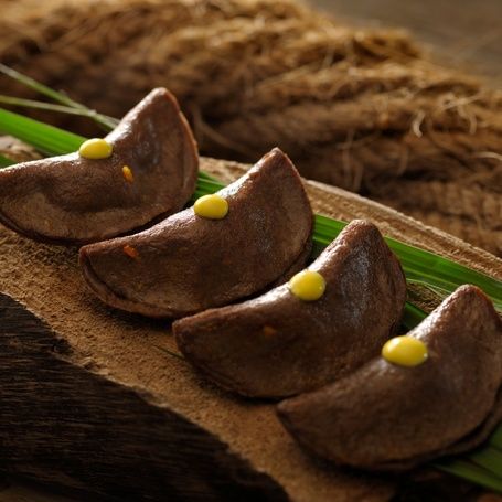 Four crescent-shaped dumplings with a yellow dot.