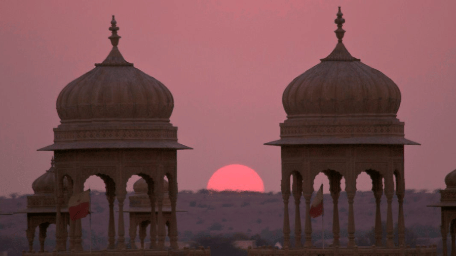 Dramatic silhouette of traditional stone monuments framing a vibrant sunset over the desert horizon.