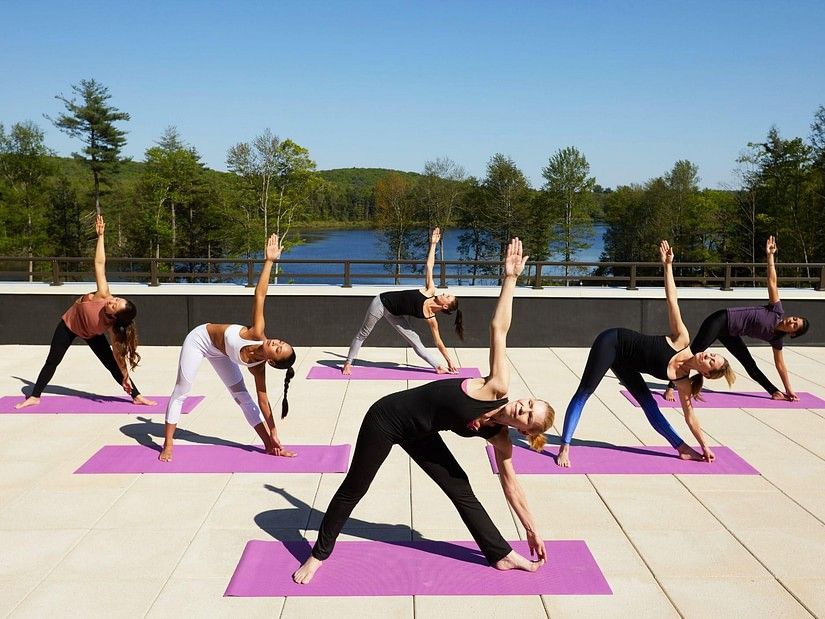 Group of people practising yoga on a rooftop with scenic views at YO1 Health Resort, Catskills, New York.