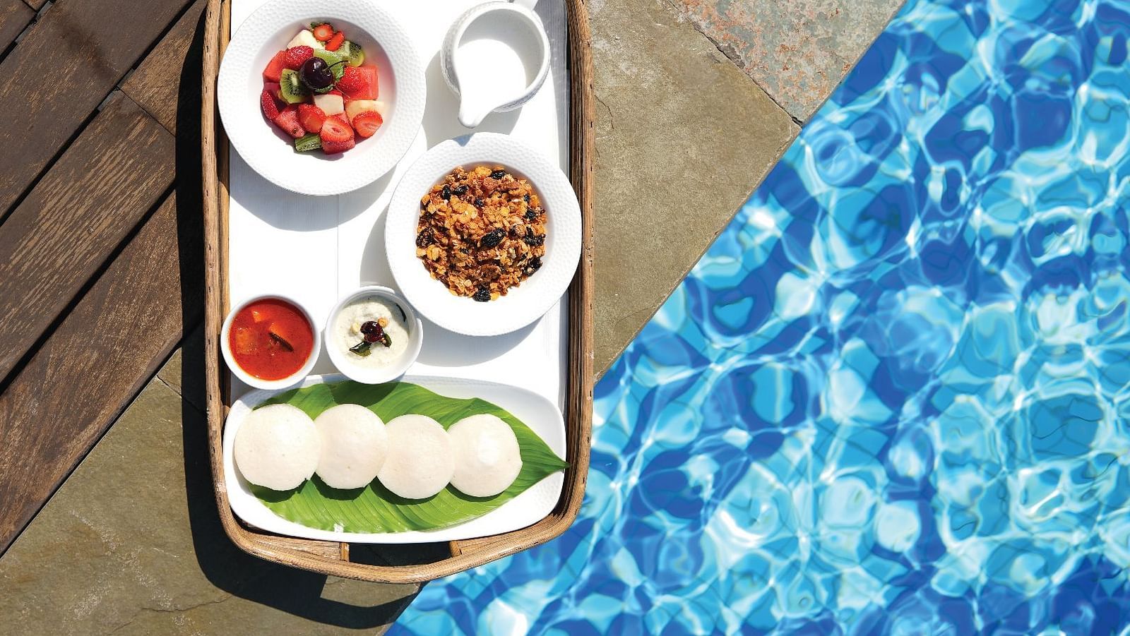 Top angle shot of a tray kept on the poolside at Miros Hotels serving breakfast by the pool.