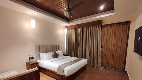 Elegant bedroom with modern wooden furniture, a king-sized bed, and soft drapes - Arina Island Resort, Swaraj Dweep