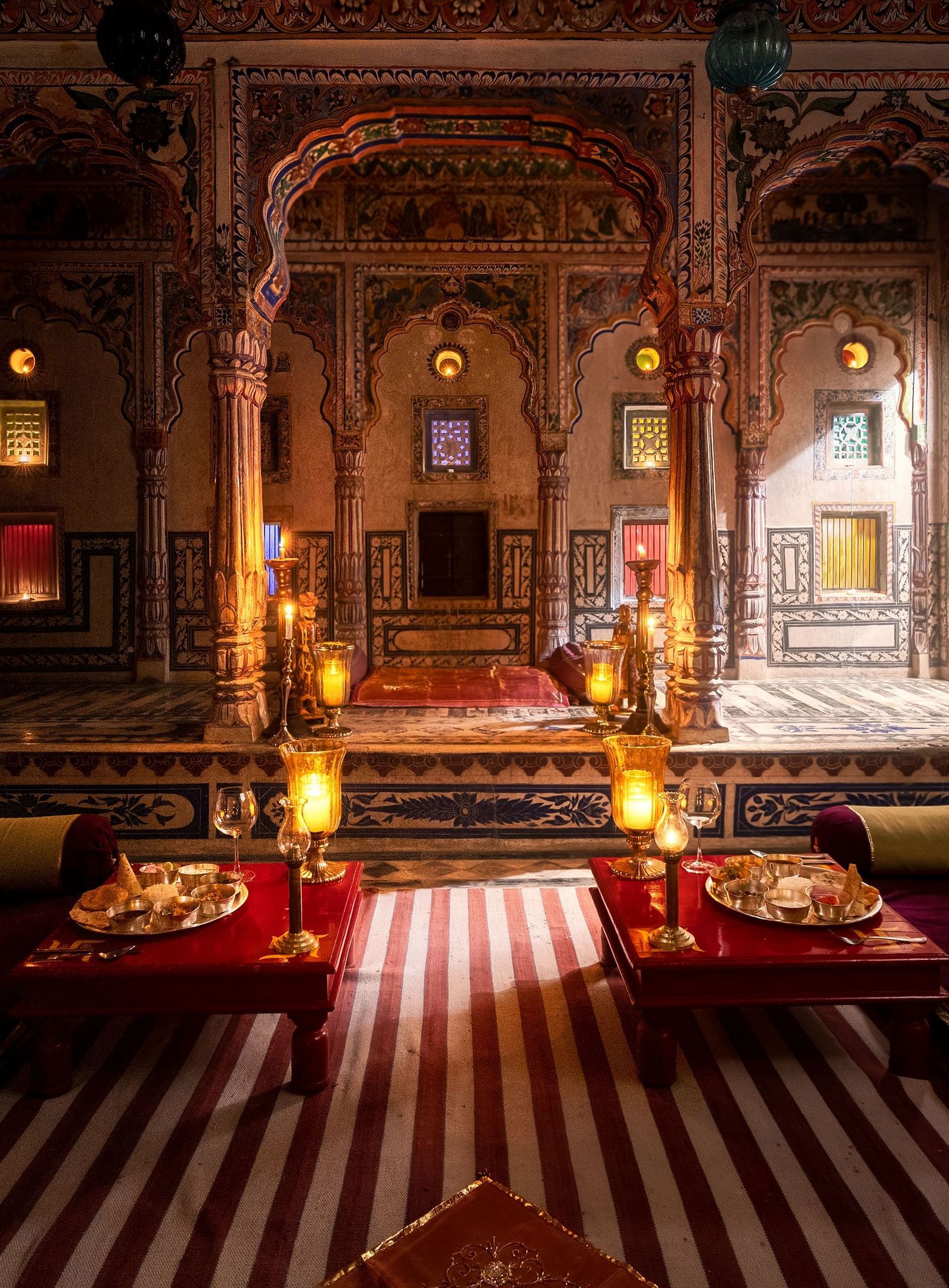A richly decorated lounge at Fort Barli, featuring ornate arches, warm lighting, and plush seating, exudes a sense of historical grandeur and intimate ambience.