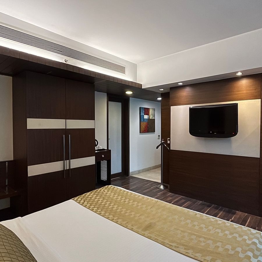 a cosy bedroom with king size bed and room amenities like a wardrobe television air purifier and wooden interior - yuhi mansions suite room1