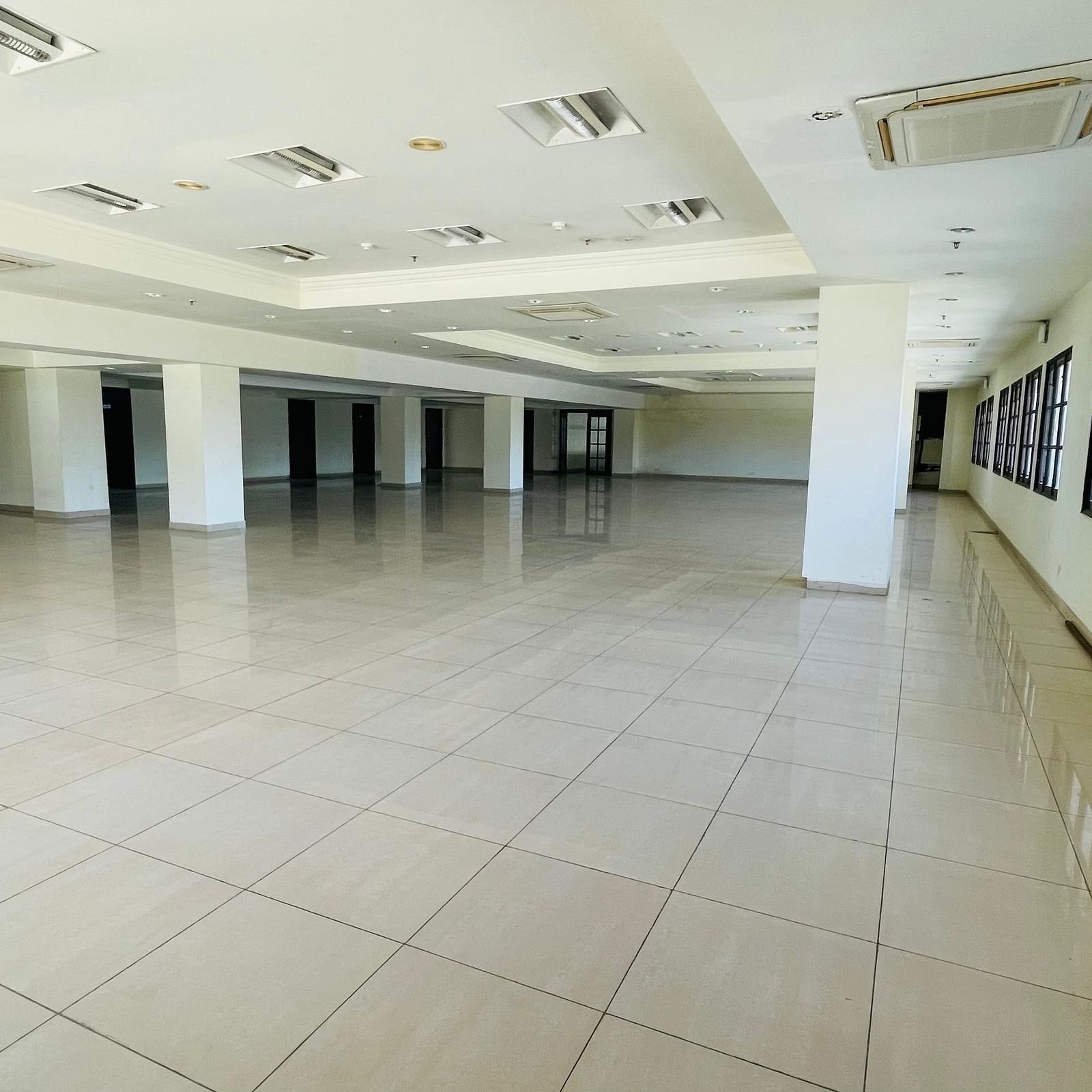 An interior view of Raj Darbar Hall with tiled floor, rows of windows and pillars.