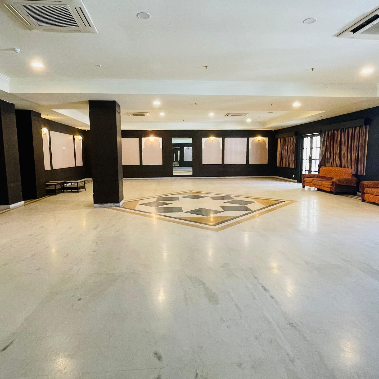 Wide view of Raj Samelan Hall at Shri Vallabh Vilas Lords Plaza Nathdwara featuring clean titled floor, with minimalistic furniture.
