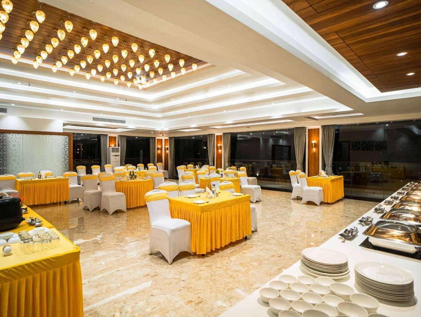 A well-lit dining area at Mansha Palace features set tables and a buffet spread ready for guests.