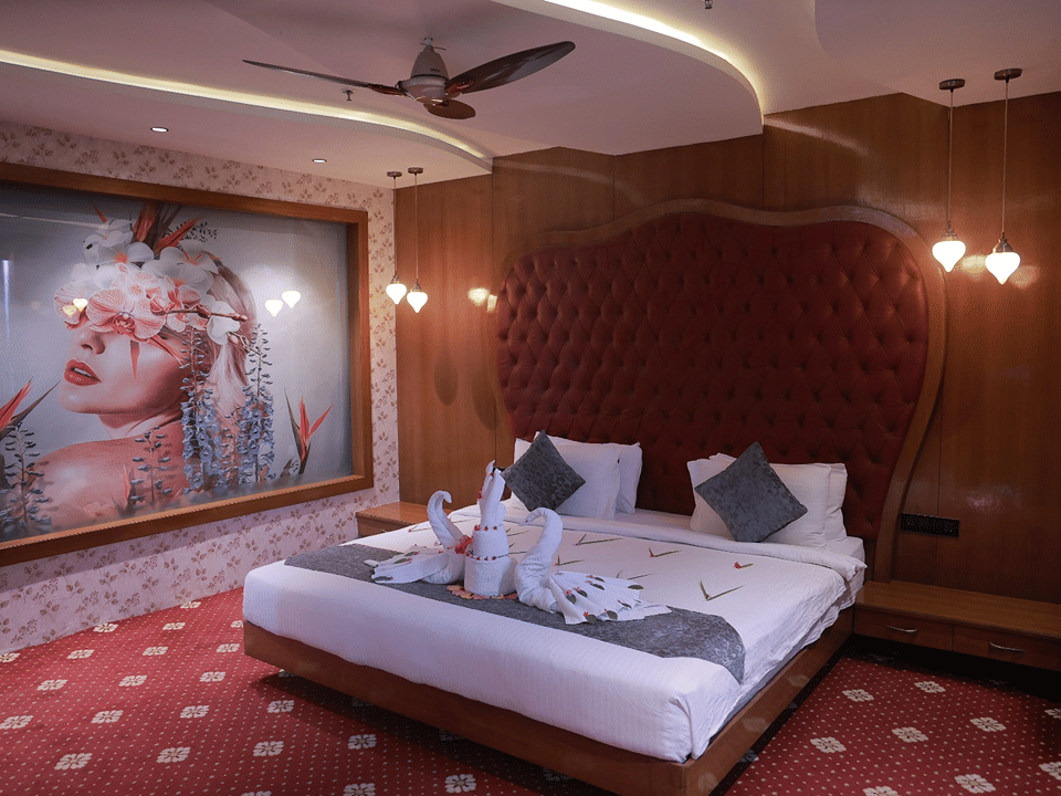 Sky Suite king bed with swan towel art, a tufted red headboard and a large floral portrait artwork