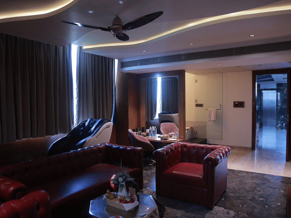 Sky Suite living area with tufted red leather sofas, a massage chair and a work desk