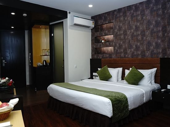 An image of Deluxe Room featuring a double size bed, bedside table on either side,  flat TV screen, AC, fruit basket and bouquets, and tea and coffee maker at Five Elements Hotels North Avenue, Delhi