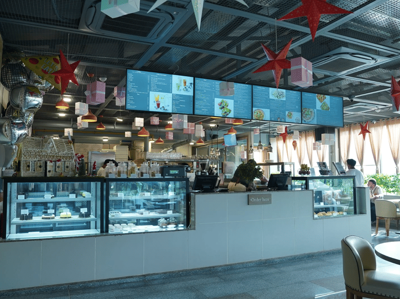 A food counter of Falaknuma restaurant with glass display units, menu boards mounted above, preparation stations, and service staff standing behind the counter at Clarks Avadh, Lucknow.