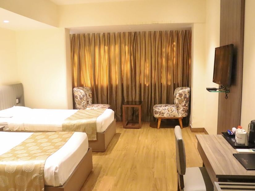Deluxe Room with twin beds having cream bed covers at Hotel Diplomat