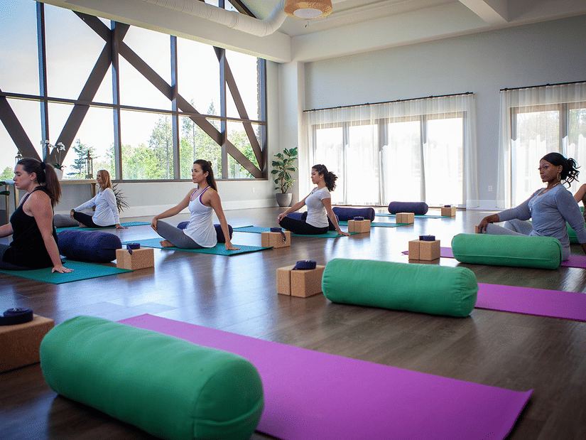 A group of people performing yoga on yoga mats indoor by a large ceiling-to-floor window at YO1 Longevity & Health Resorts