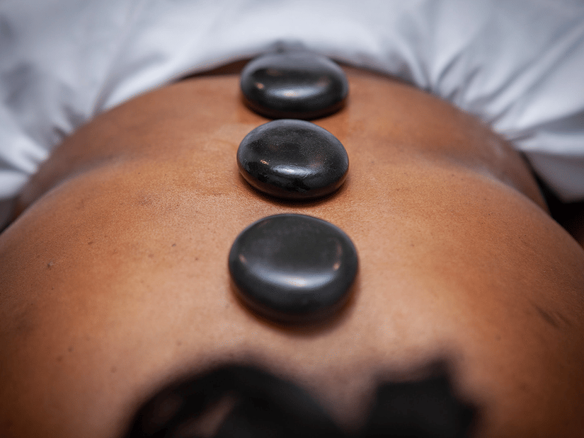 Three hot stones placed down the back of a person lying on their stomach at YO1 Longevity & Health Resorts