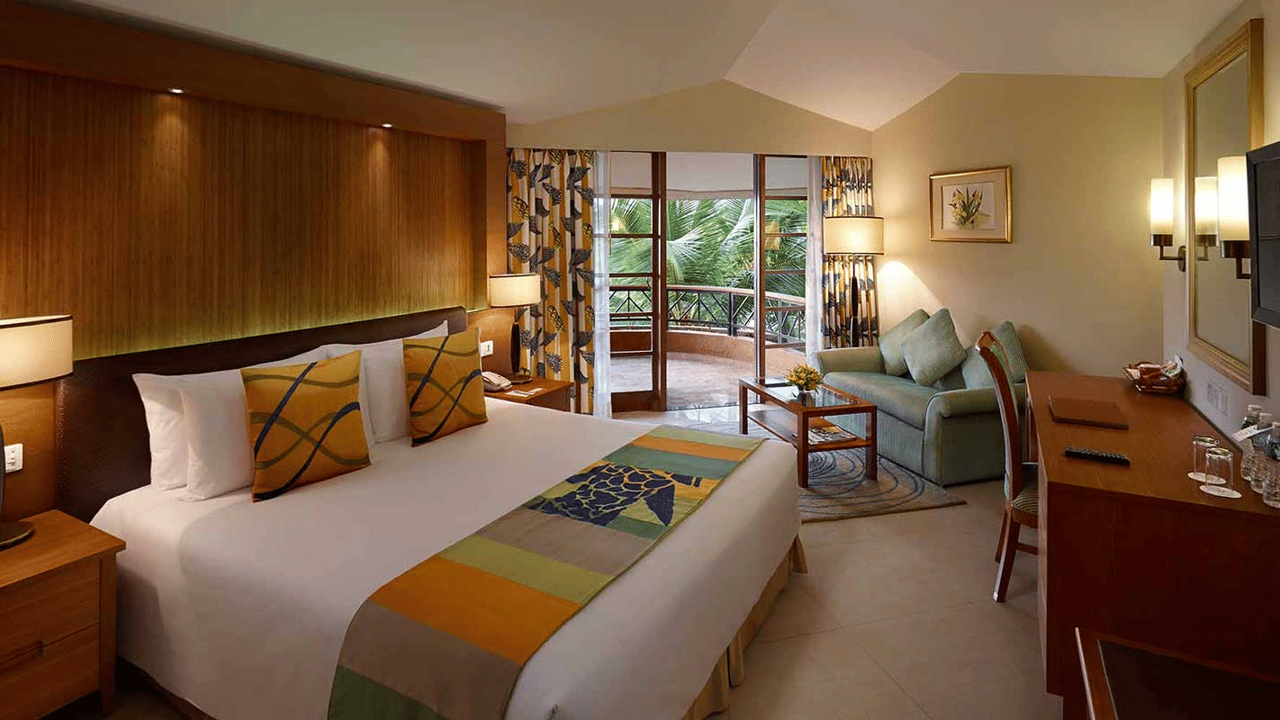 a double bed with side tables and lamps on it inside pool-view room in South Goa - Caravela Beach Resort, Goa