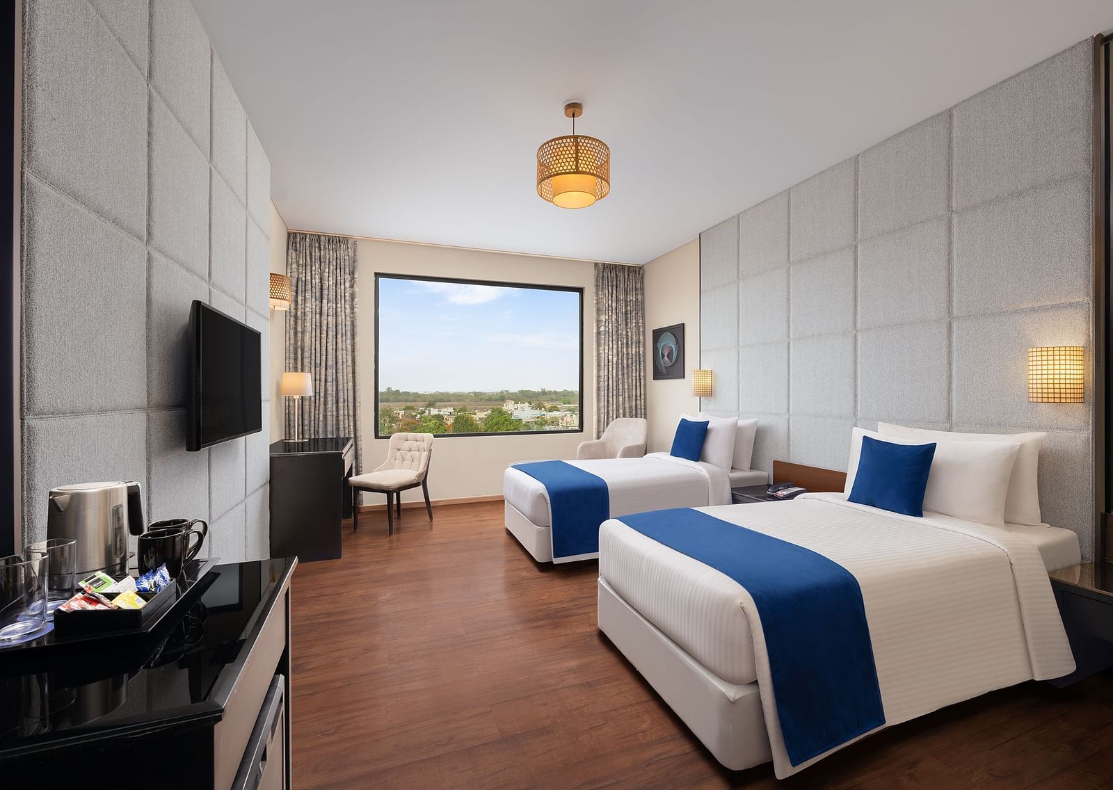 Deluxe Twin Room at Essentia Luxury Hotel, Indore with twin beds, a television and a work desk and chair