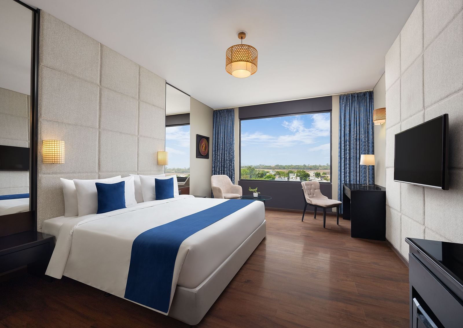 Deluxe king room at Essentia Luxury Hotel, Indore with a double bed and a television