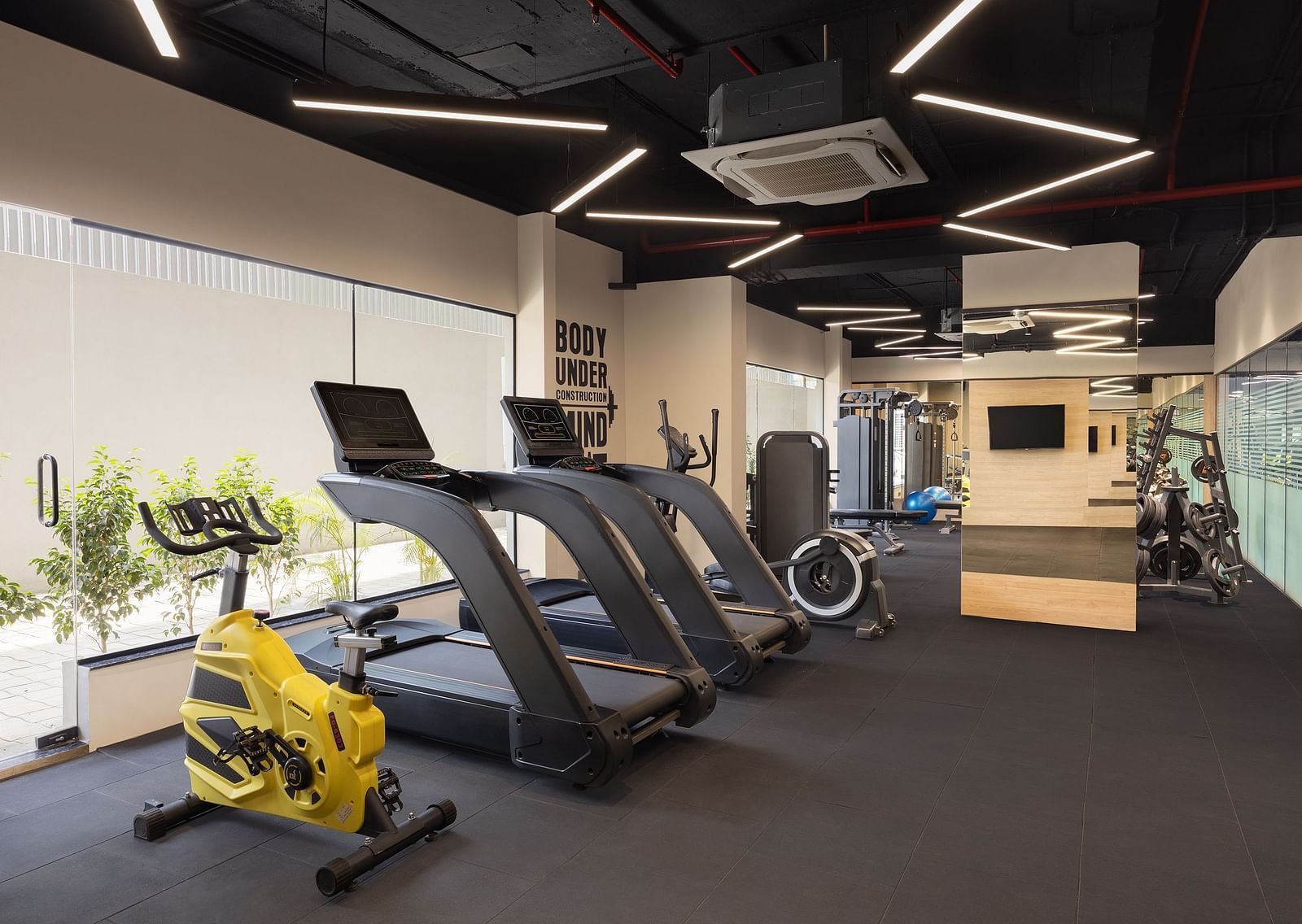 Gym at Essentia Luxury Hotel, Indore with cardio equipment placed near the windows