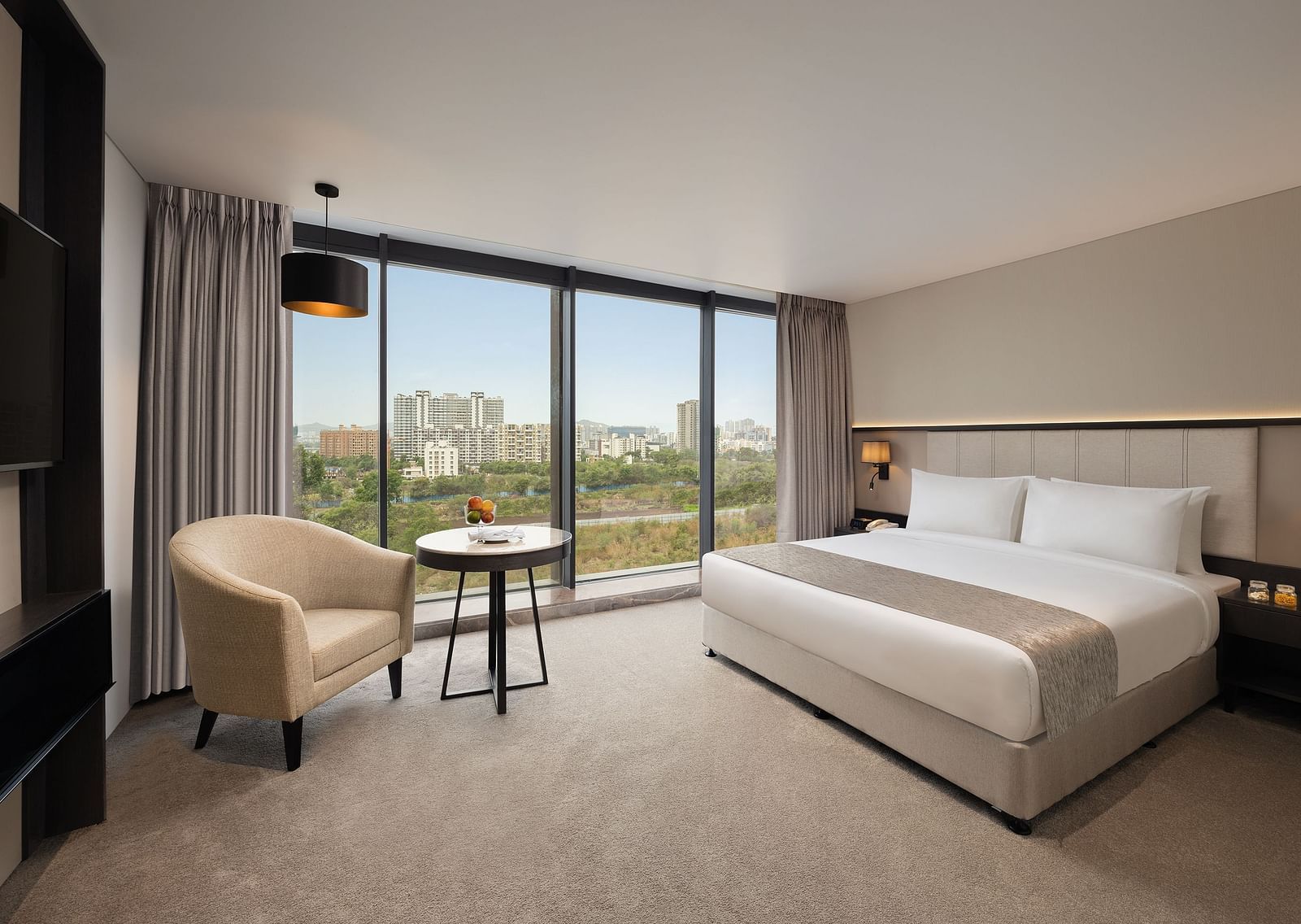  Premier Room with a king size bed and a sofa beside a large window at Essentia Premiere, Pune.