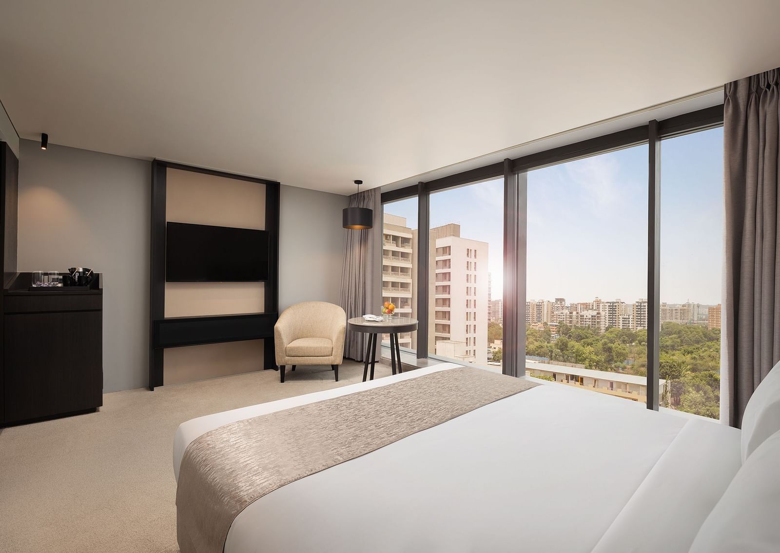 Premier Room with a king size bed and a view through a large window at Essentia Premiere, Pune.
