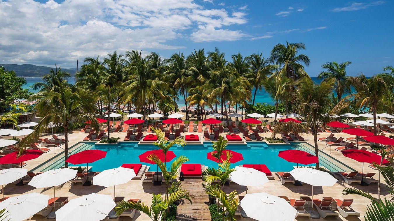An aerial shot of a swimming pool area with sun loungers and palm trees - S Hotel Montego Bay, Jamaica