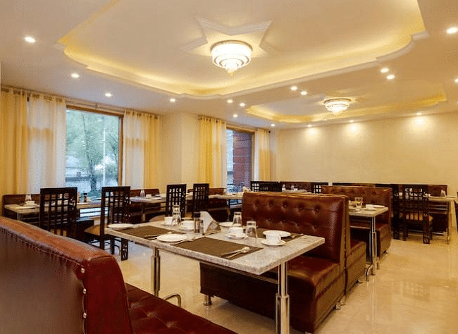 A dining area in La Serene Valley Resort in Manali. The dining room is well-lit and dining tables. | DLS La Serene Manali