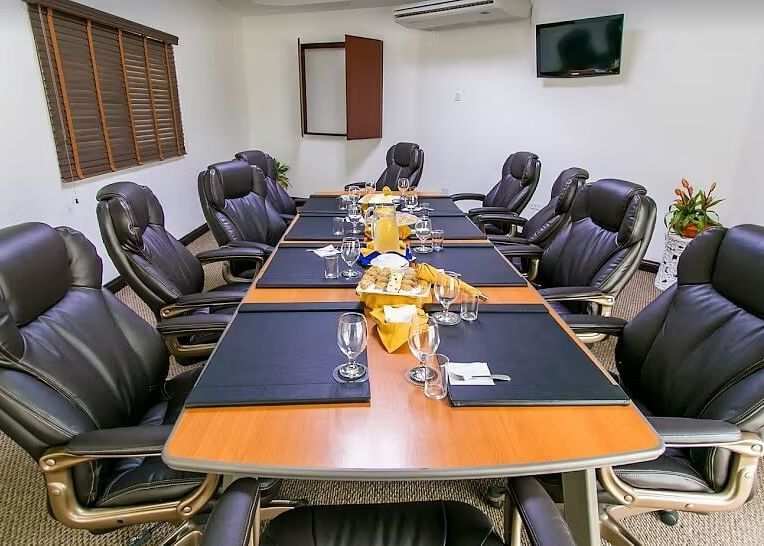 A conference room features a long, dark wood table surrounded by black office chairs | Board Room | Altamont Court, Jamaica