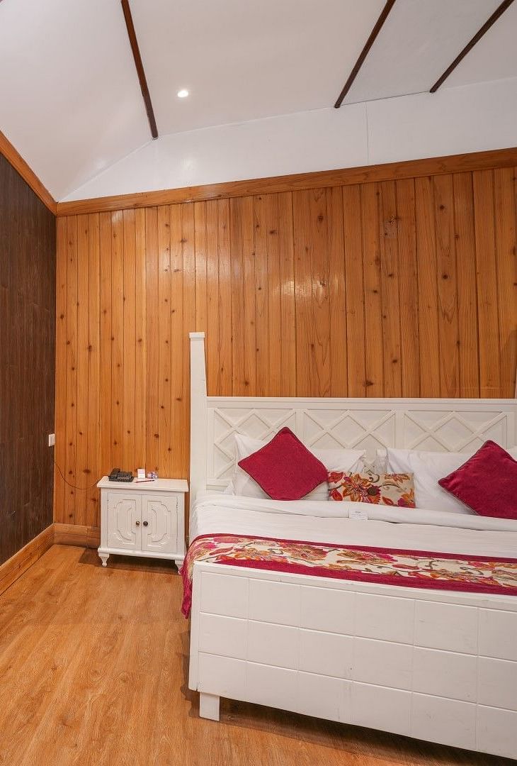 A room at Summit Barsana Resort & Spa, Kalimpong wih a double bed, a large window and wooden panelling