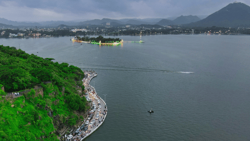 Aerial view of the curved, tree-lined promenade along the scenic Fateh Sagar Lake in Udaipur.