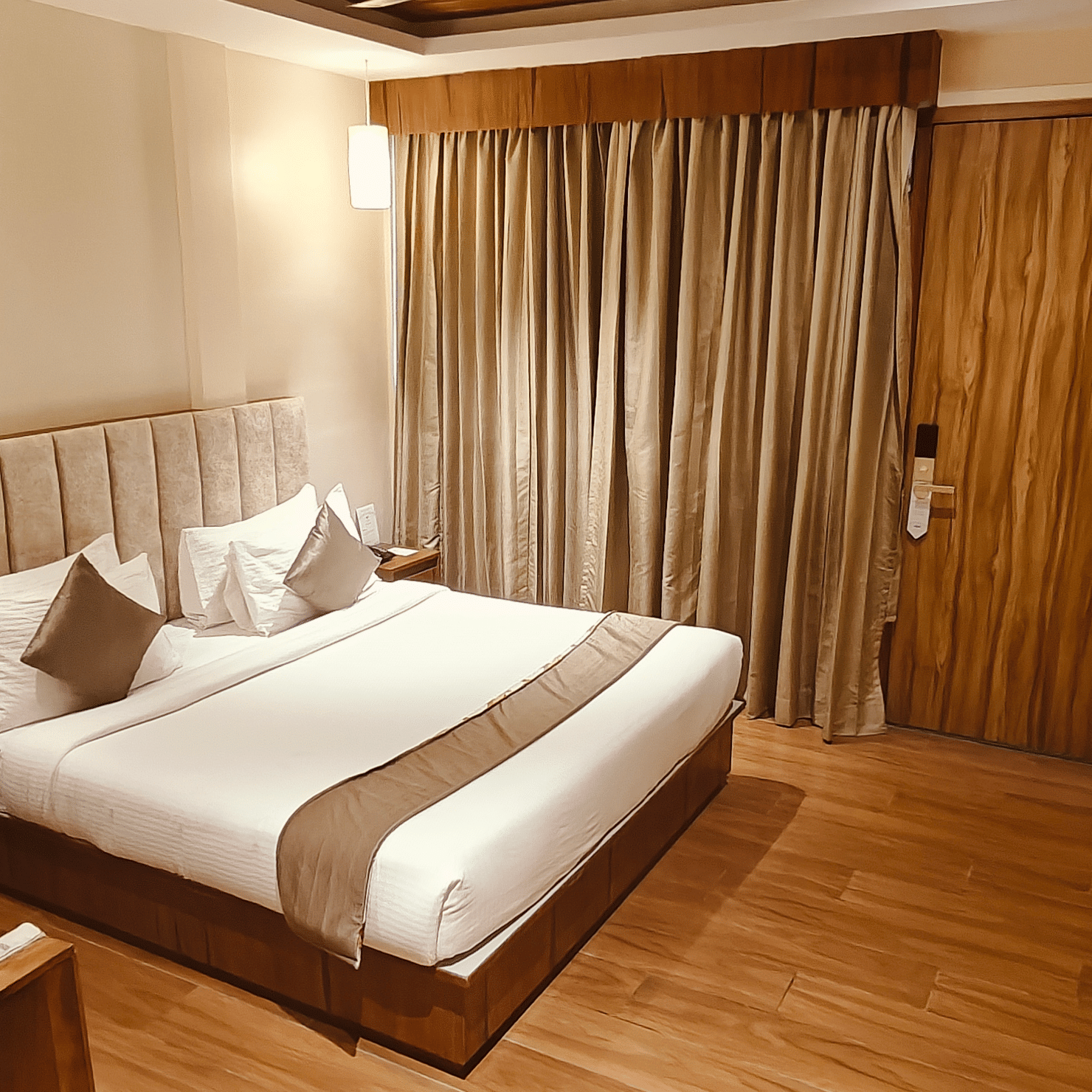 A well-lit bedroom at Red Skin Villa featuring a double bed, wall-mounted TV, and wooden interiors