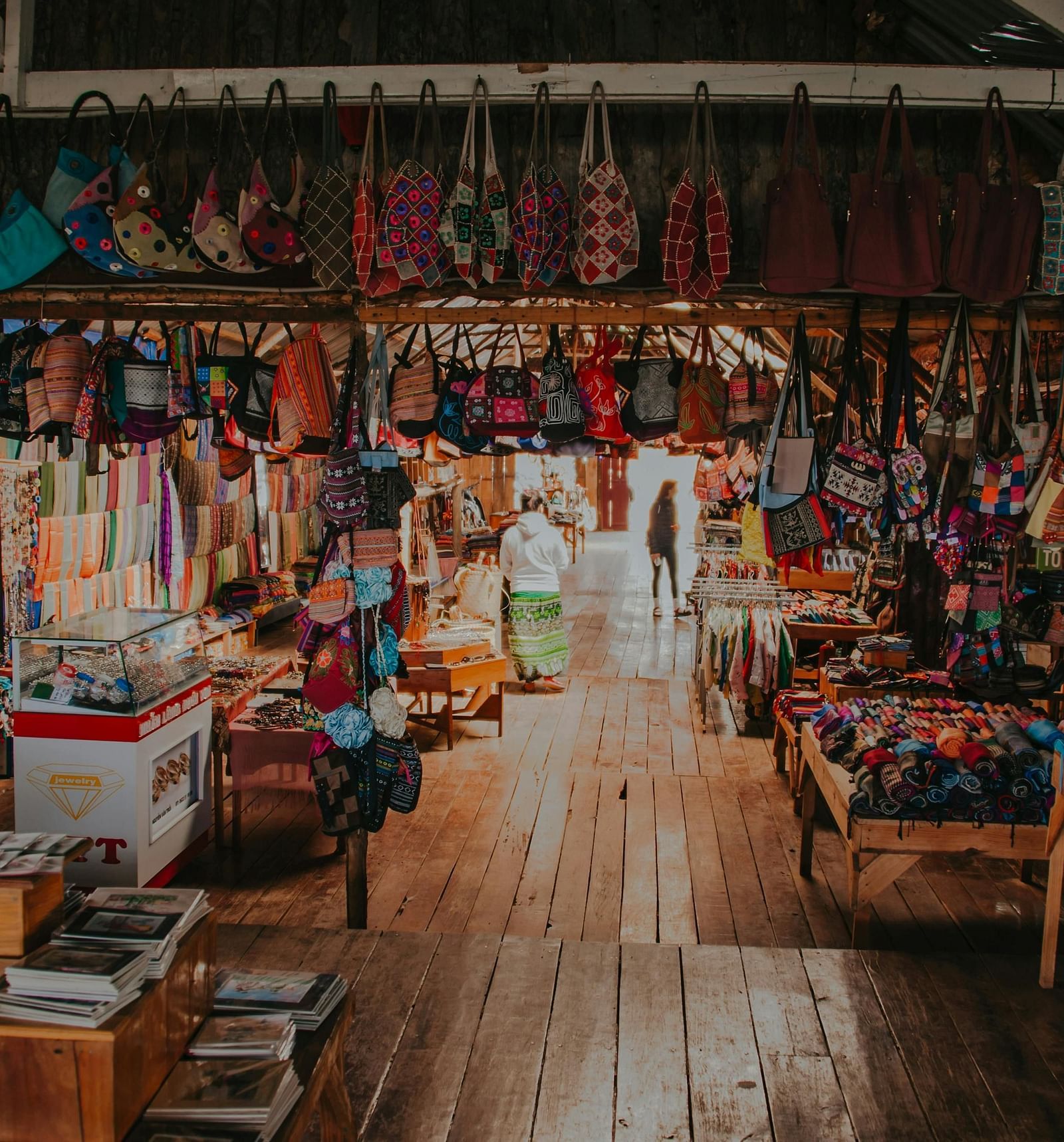 An indoor market with stalls selling colourful fabrics and goods.