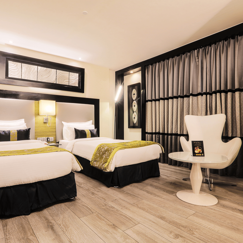 Executive Twin Room at The Empresa Hotel featuring two similar looking bed, and a chair with centre table.