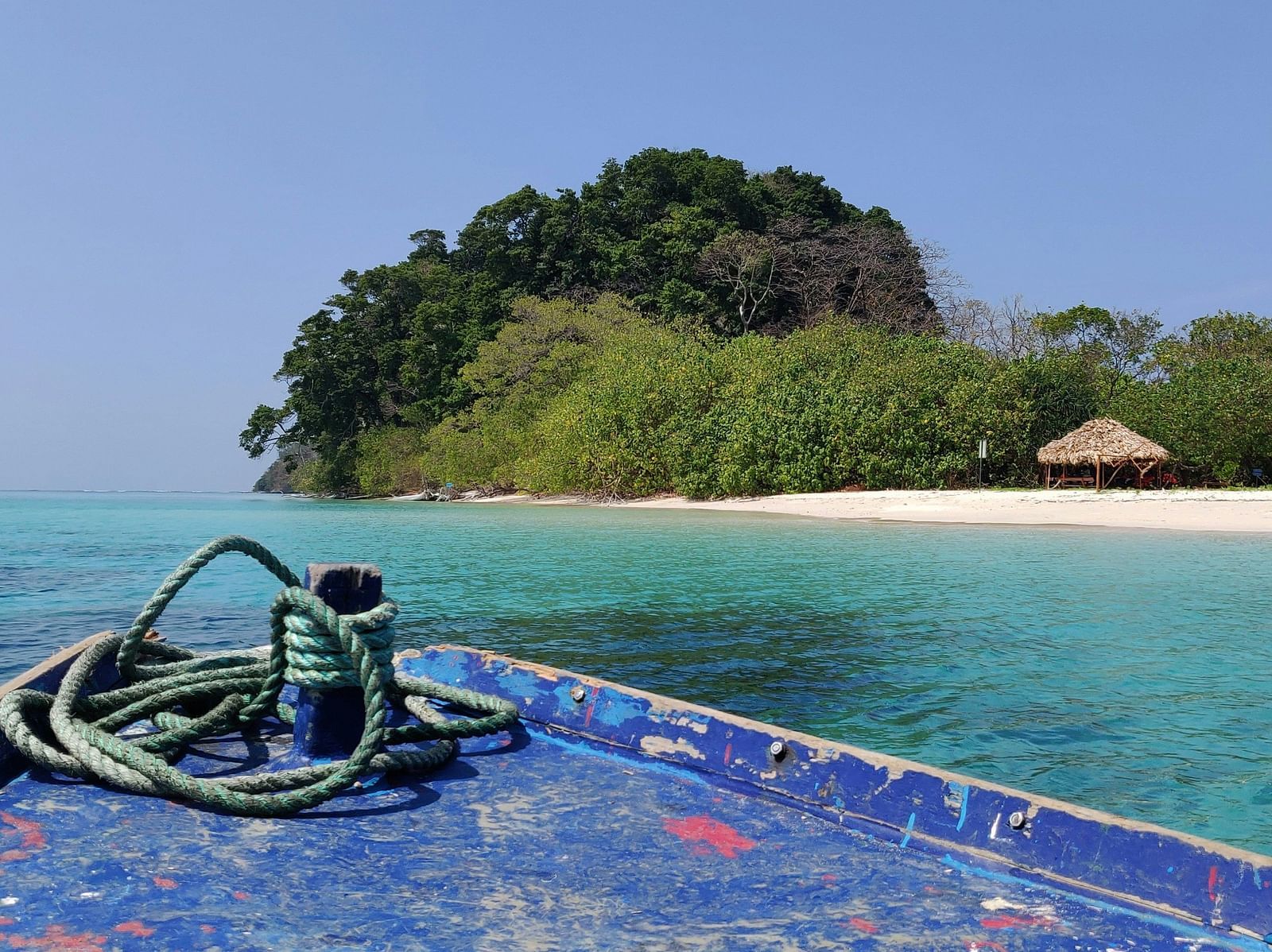 An island seen from a blue boat travelling towards it