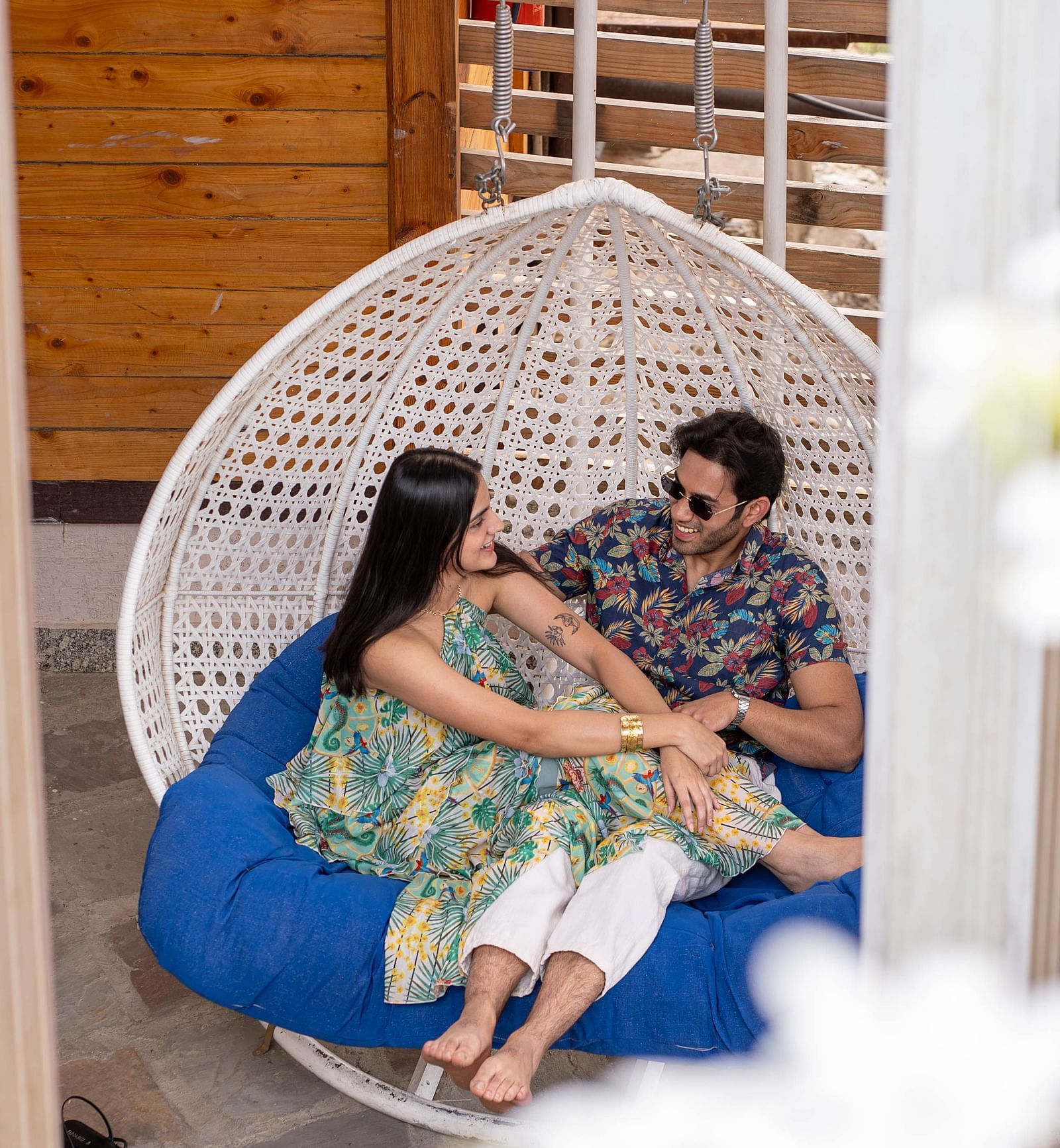 A man and a woman looking at each other and smiling in a swing.