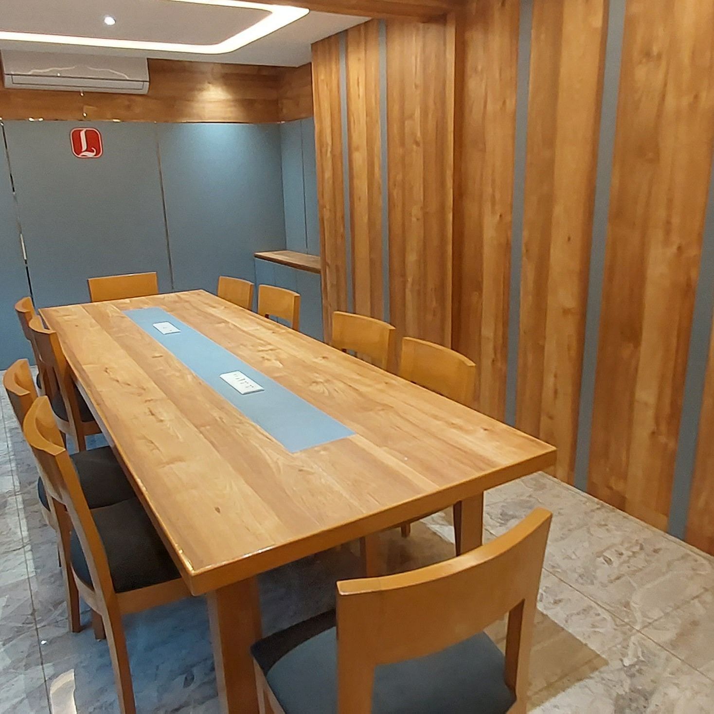 A side angle view of a well furnished boardroom at Lords Eco Inn Dahej, featuring wooden furniture, and roof light.