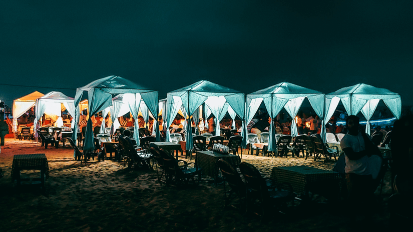 a beach shoreline dotted with well-lit stalls