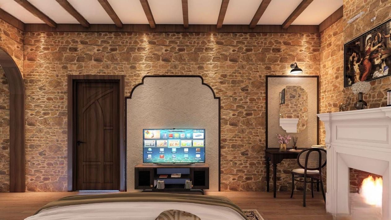 Rustic bedroom featuring a stone-clad wall, exposed timber beams, a fireplace, and a television recessed in an archway at BluSalzz Terrah Hills Resort, Dalhousie.