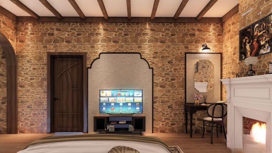 Rustic bedroom featuring a stone-clad wall, exposed timber beams, a fireplace, and a television recessed in an archway at BluSalzz Terrah Hills Resort, Dalhousie.
