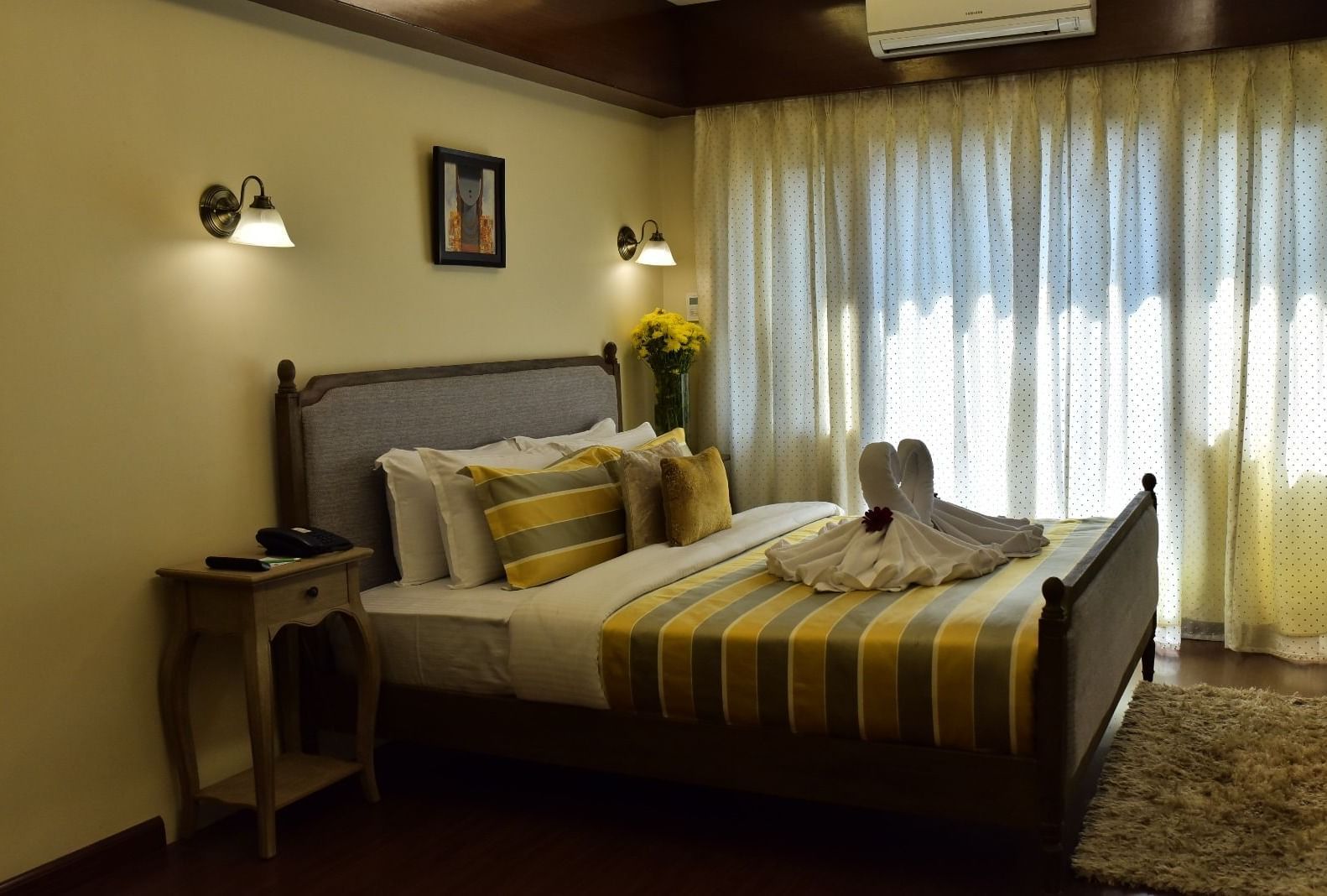 A well-appointed room at Polo Hotel Shillong with a double bed, warm lighting, and bright yellow cushions.