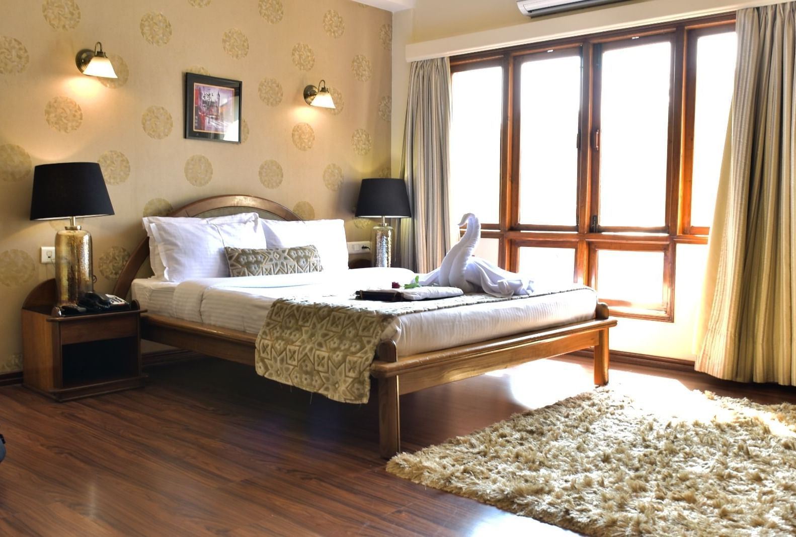 A spacious and bright room at Polo Hotel Shillong with a double bed, bedside lamps, and a large window.