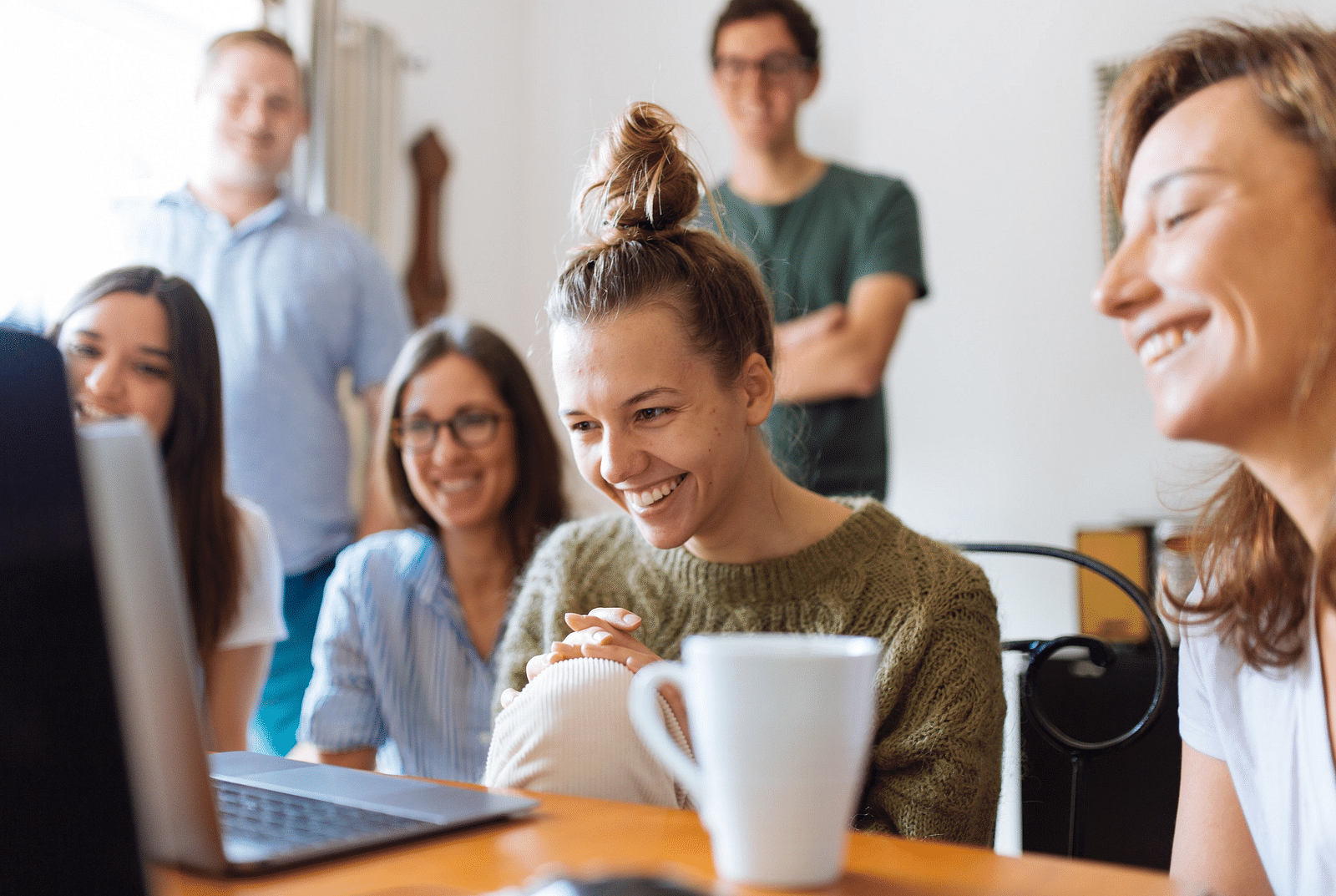 a group of people watching a laptop screen with smiles on their faces