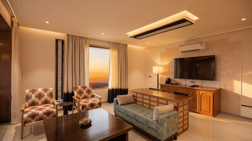 A sitting room displaying a sofa with a wooden back, 2 patterned armchairs, and a wall-mounted television at The Sierra - By The Lake.