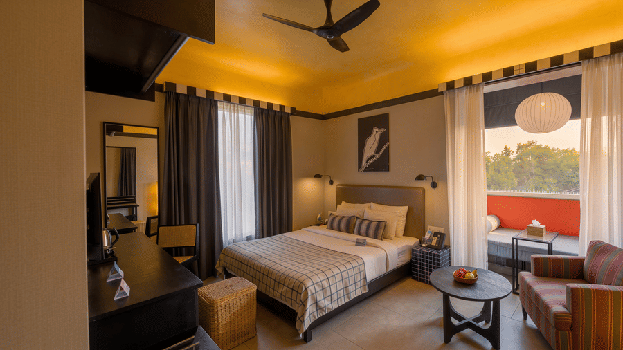 A hotel room containing a king size bed, a ceiling fan, a small coffee table, and an armchair next to a balcony at The Sierra - By The Lake.