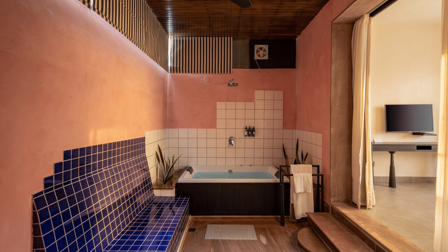 A relaxing bathing area with a dark bathtub, tiled walls, overhead shower, and open doorway at The Sierra - By The Lake.